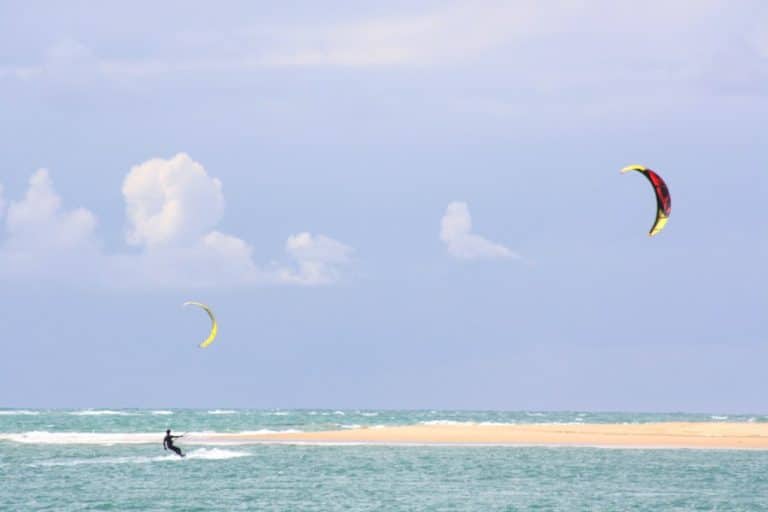 Vacation scene: kitesurfs on the ocean at the sea on the beach of La Barrosa in Sancti Petri, Chiclana de la Frontera, Andalusia, Spain. Best Places To Get Lost In Andalusia This Summer