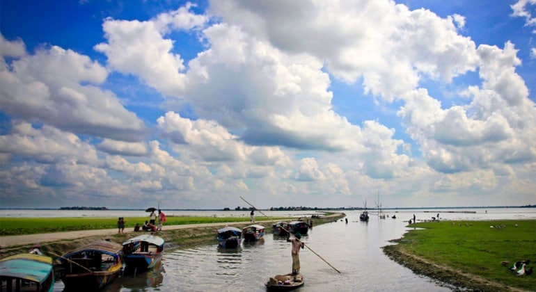 Stunning Chalan Beel/চলন বীল in Natore with her beauty. Boatmen are boating and the sky is covered with thick white clouds.