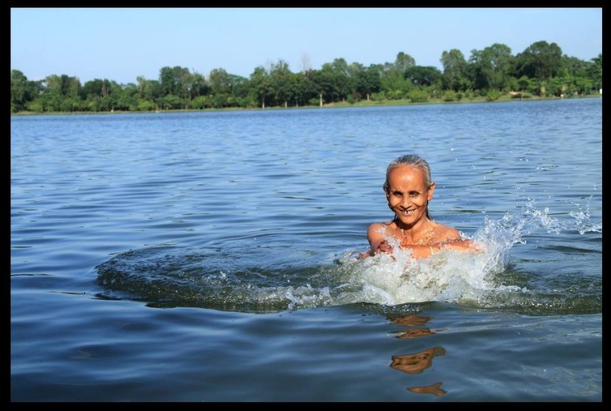 An old woman is bathing in Nilsagar in Nilphamari. Depicts the beauty of nature and people.