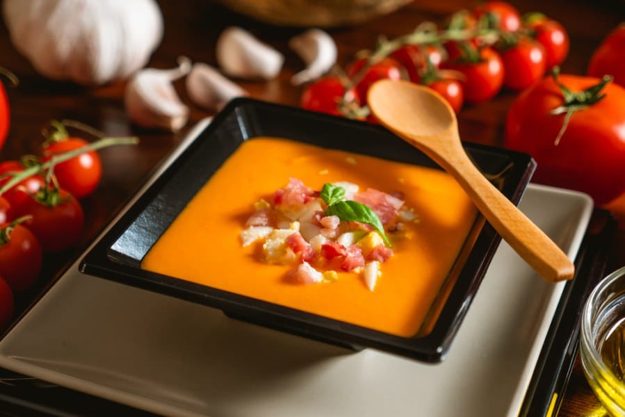 Typical spanish recipe for cordovan salmorejo in a square plate with some ingredients around.