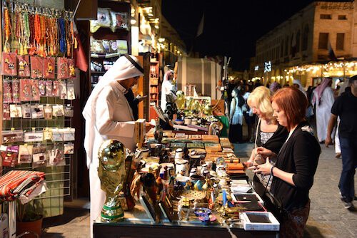 People shopping at a vibrant night market, lit up by colorful lights