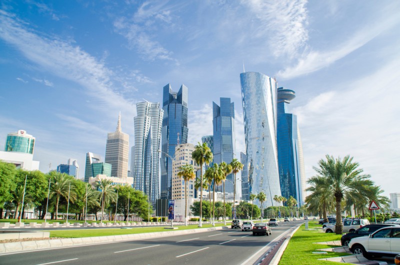 a road with cars and tall buildings in the background