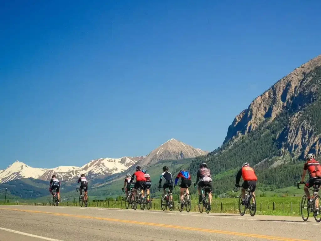 A pack of cyclists cruising down a road with mountains in the backdrop