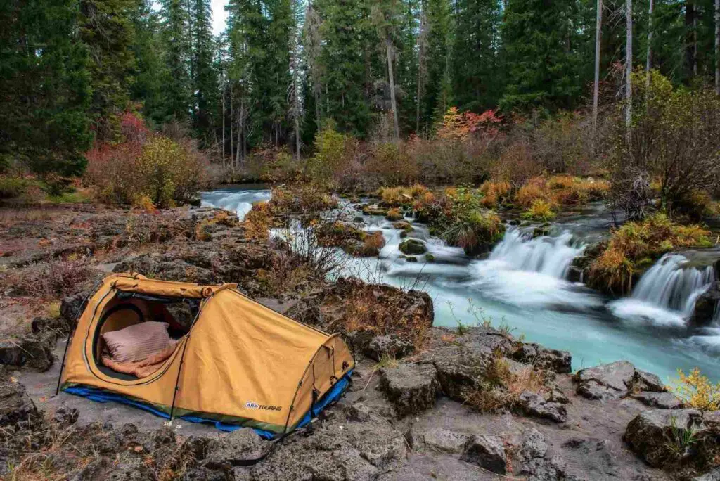 A tent set up in front of a waterfall.