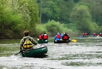 a group of People in canoes paddling down a river
