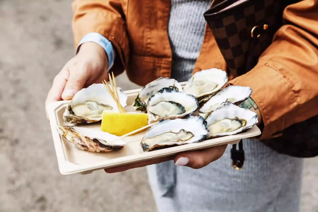 person holding a plate of oysters